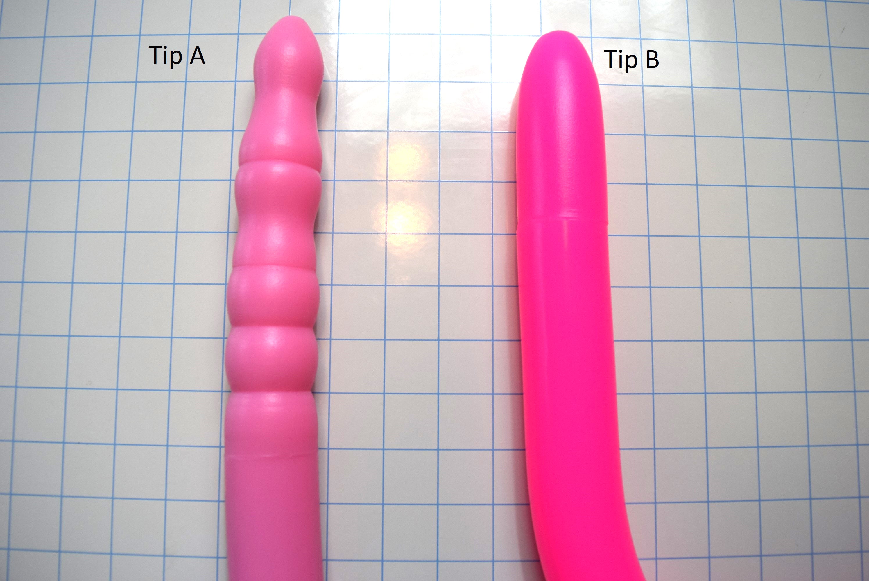 Comparison of Tip A and Tip B 1.6 inch silicone colon tube designs, showing pink tip A and fluorescent pink tip B, and  on a grid background