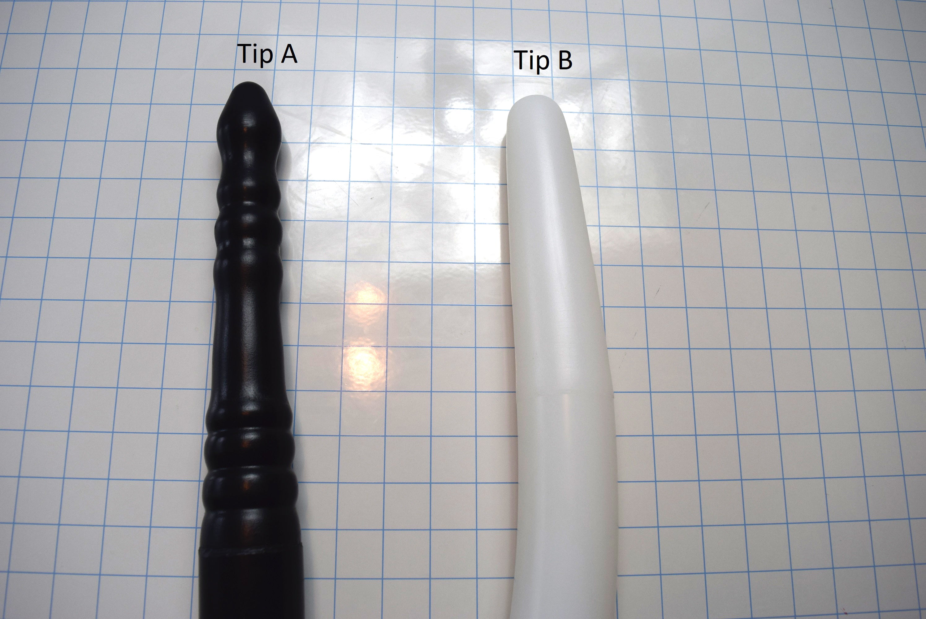 Comparison of Tip A and Tip B 2-inch silicone colon tube designs, showing black tip a, translucent white tip b on a grid background