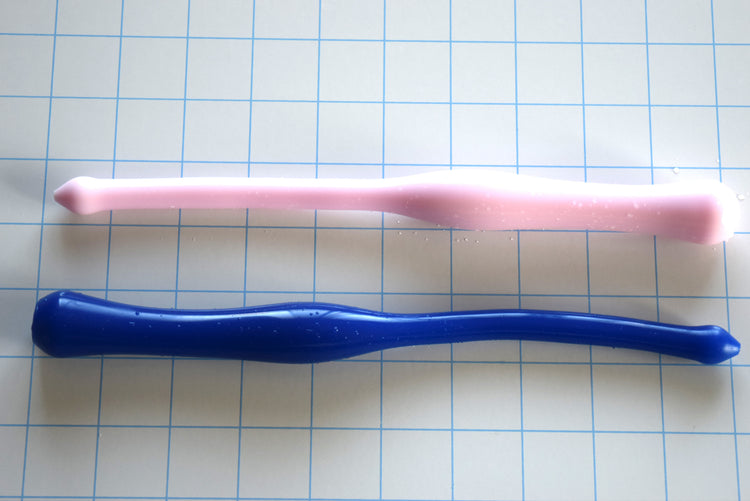 Pink and dark blue SSND-MGCWAND13 silicone sounds, 9.5 inches long, featuring a 13mm tip, 21mm oval expansion, and retention valley on a blue grid background.