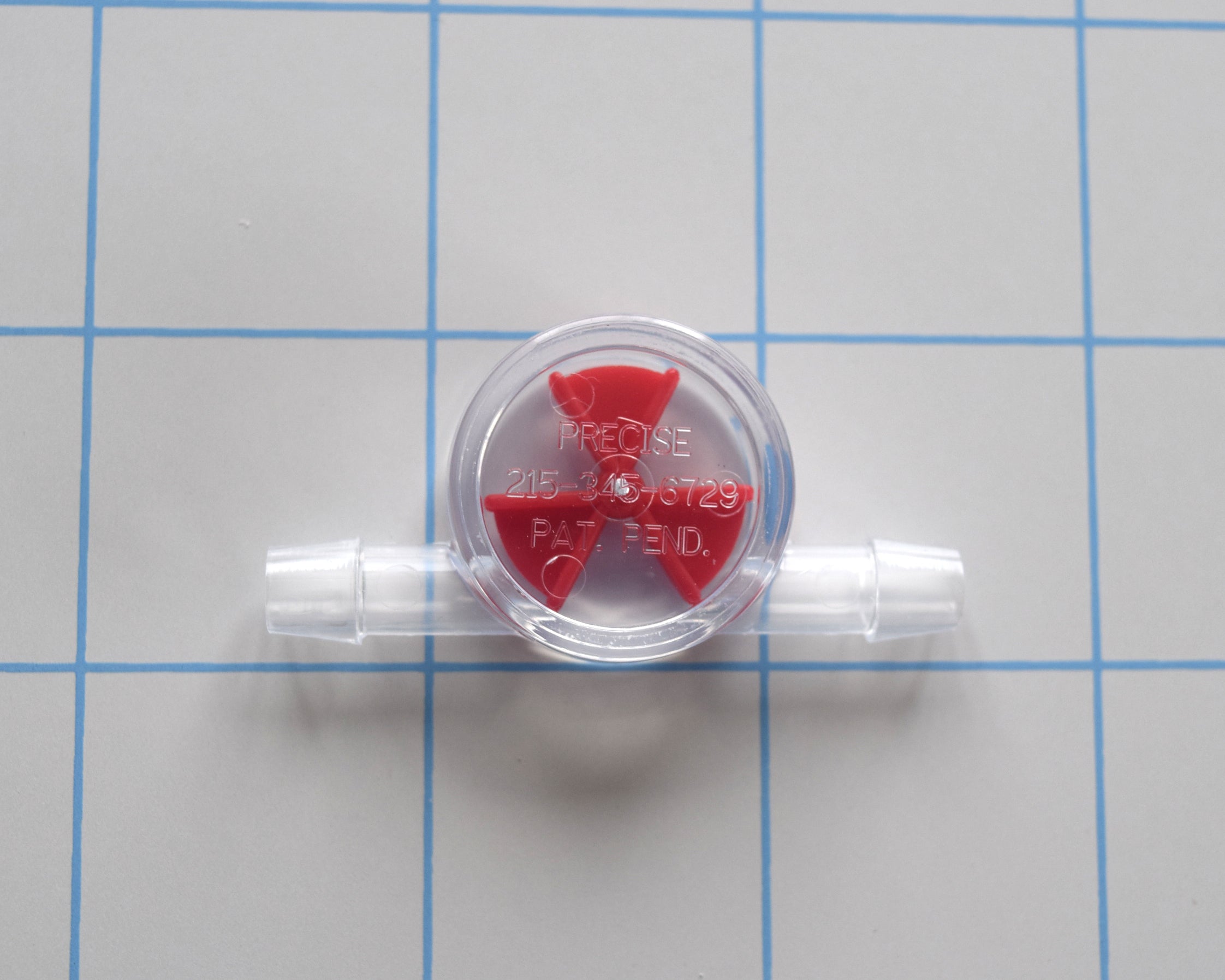 Inline liquid flow indicator for 1/4 inch tubing with a clear body and a small red wagon wheel style spinner paddle, shown on a white background.