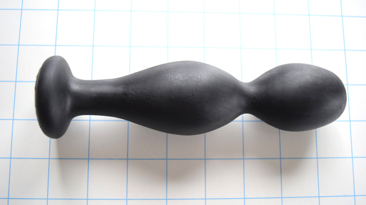 Balltip Medium black silicone enema nozzle featuring a 1.6-inch primary round tip, a 3/4-inch valley, a 1.7-inch secondary expansion bulb, and a wide 1 15/16-inch safety base flange on a blue grid background.