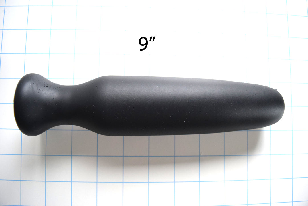 Black silicone CSRE colonic speculum retention enhancer 9-inch long-format version displayed horizontally on grid background with 9-inch measurement text overlay