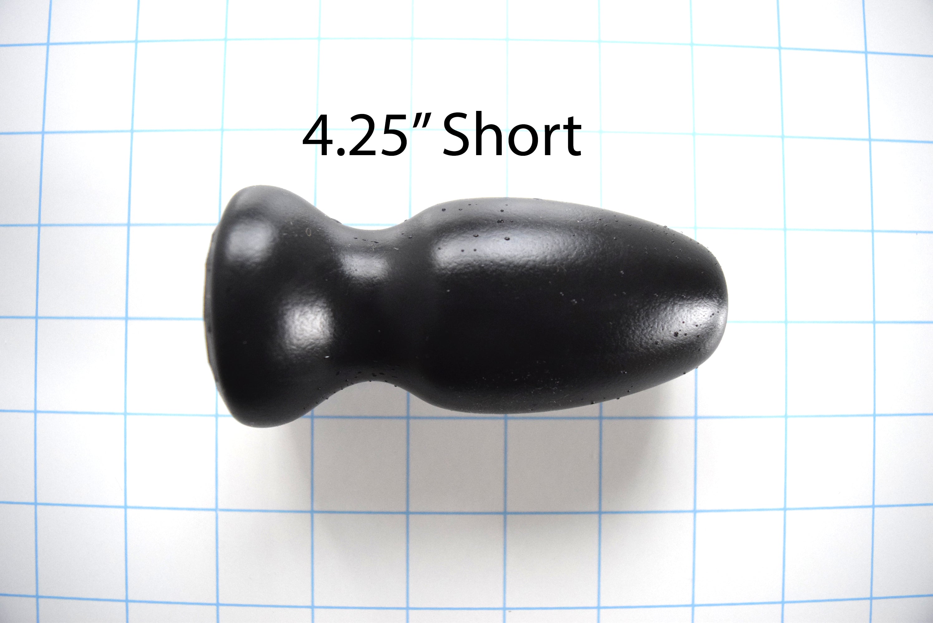 Black silicone CSRE colonic speculum retention enhancer, 4.25-inch short version, displayed on a blue grid background with a 4.25-inch short text measurement overlay.