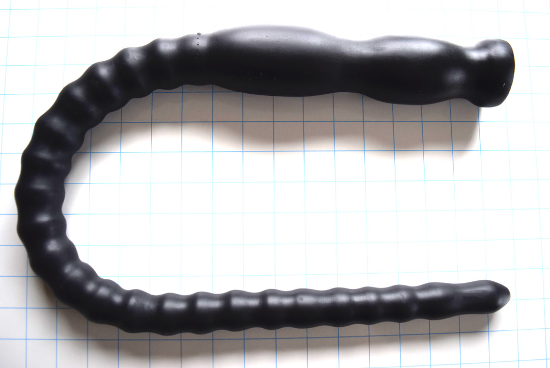 CT80-122 French 34-inch tapered ribbed colon tube in matte black silicone on a blue grid background, showing the shaft expanding from 1-inch to 1.6-inch diameter with 2.25-inch double retention balls.