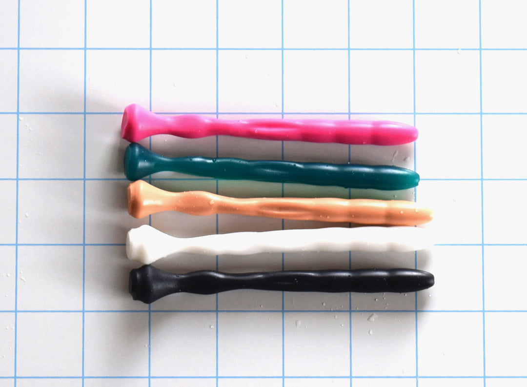 SSND-Dimpled short flexible silicone urethral sound shown in multiple colors on a grid background, highlighting its 5mm rounded tip, 9.25mm dimpled textured shaft, and a narrow 4.75mm flattened billow section leading to a 14.5mm safety base flange.
