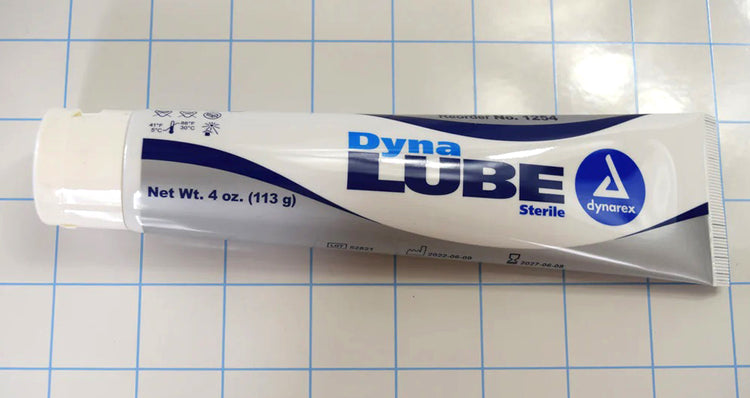 Horizontal view of a 4 oz tube of Dynalube sterile lubricating jelly on a blue grid background.