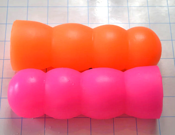 ED-ESS 1 6-inch enhancement sleeves displayed in fluorescent orange and fluorescent pink color variants on a blue grid background, showcasing ergonomic palm-contoured grips and multi-textured core options.