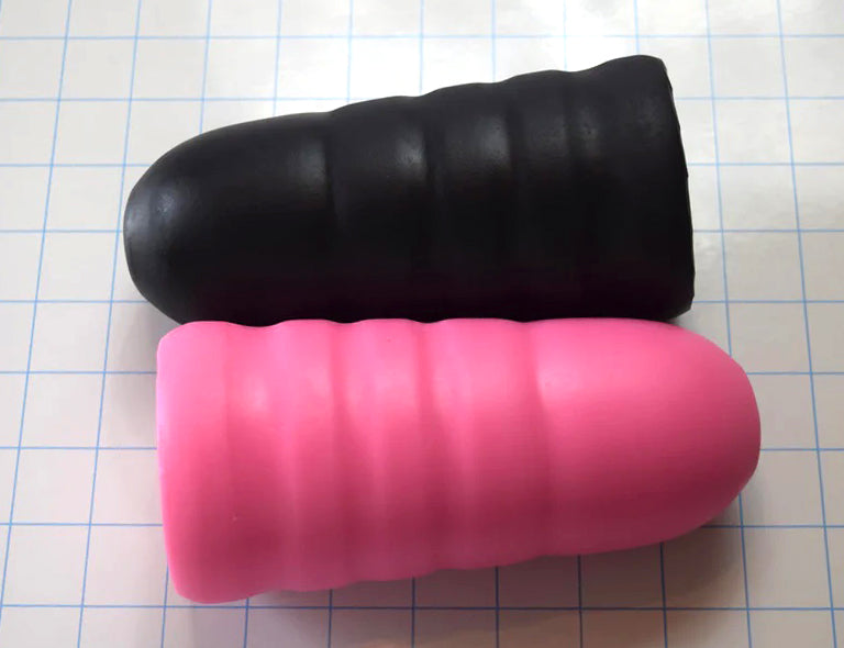 Overhead angle view of the black and pink ED-ESS 5 silicone stimulation sleeves showing their textured exterior valleys on a blue grid background.