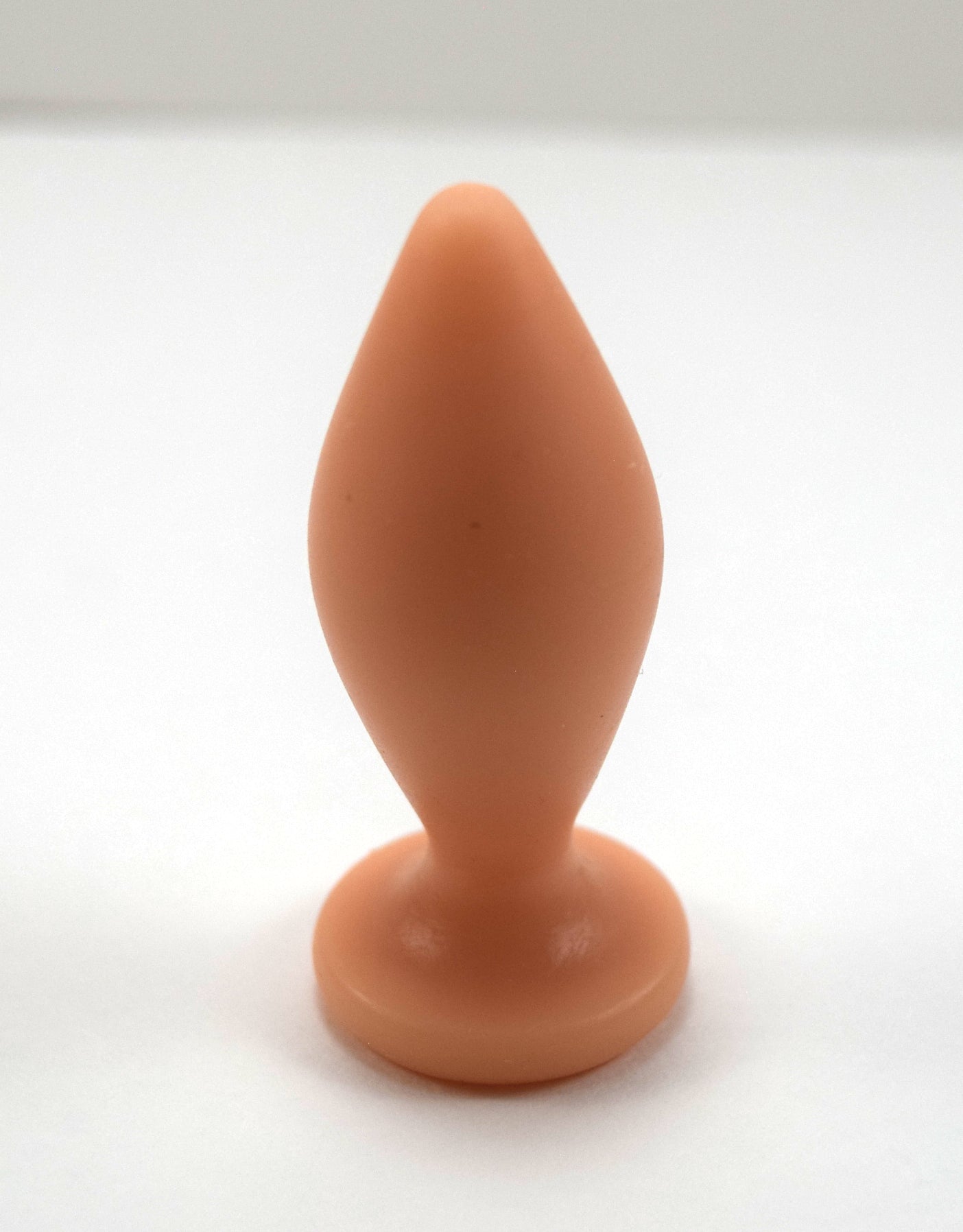 Expanded Diamond 1-inch flesh silicone retention nozzle featuring a wide faceted diamond body, 2-inch insertable length, ultra-slim retention valley, and flat safety flange on a grid background.