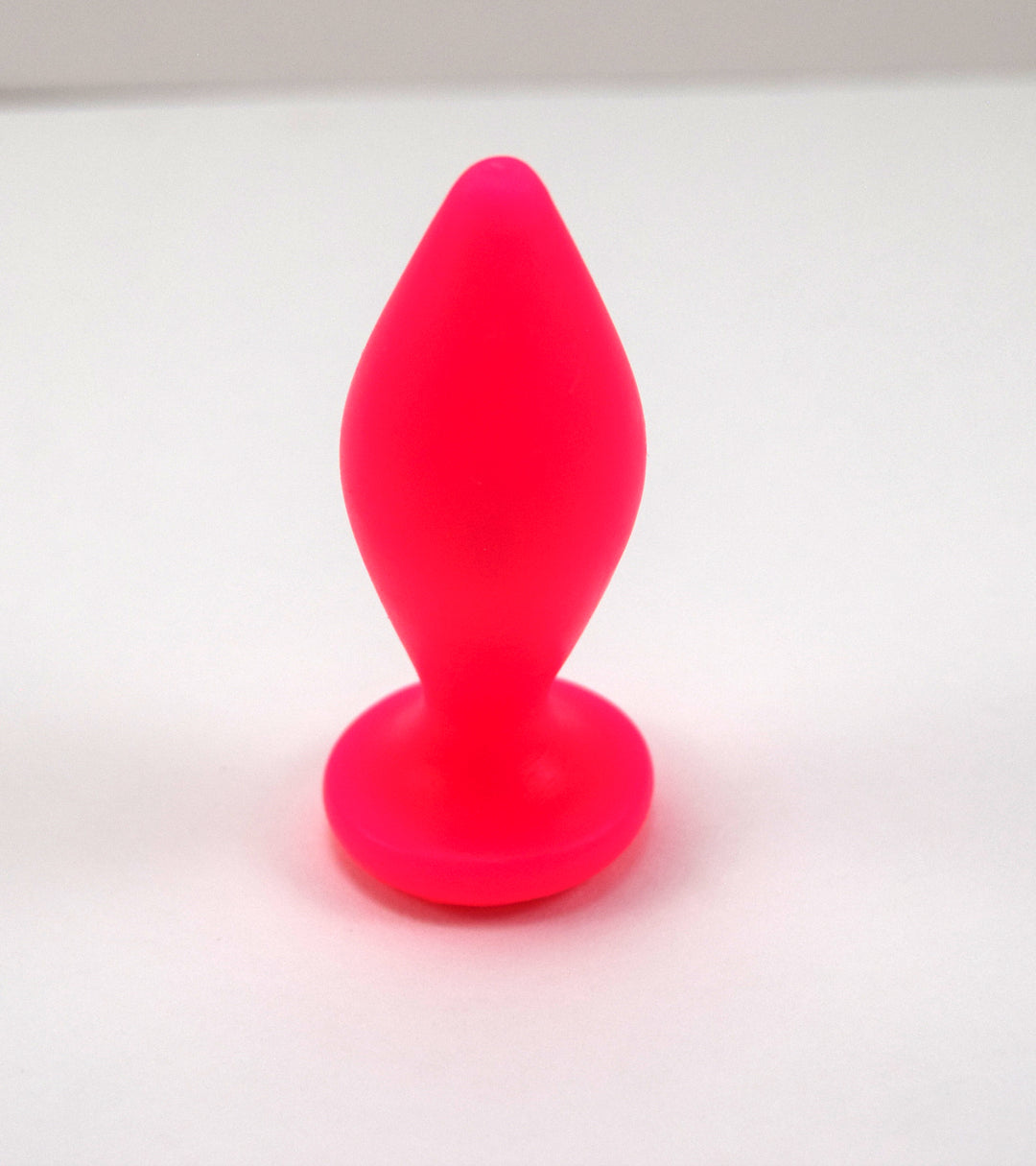 Expanded Diamond 1-inch fluorescent pink silicone retention nozzle featuring a wide faceted diamond body, 2-inch insertable length, ultra-slim retention valley, and flat safety flange on a grid background.