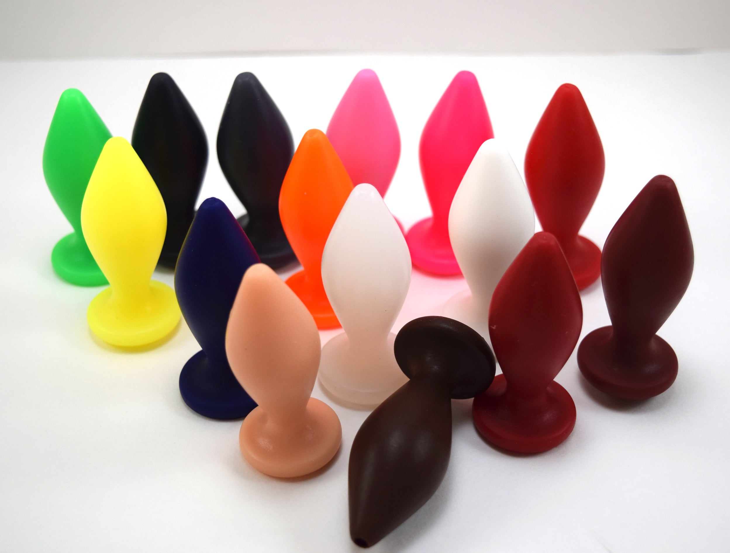 A collection of silicone enema nozzles in various colors, with a diamond-shaped body and a tapered tip.