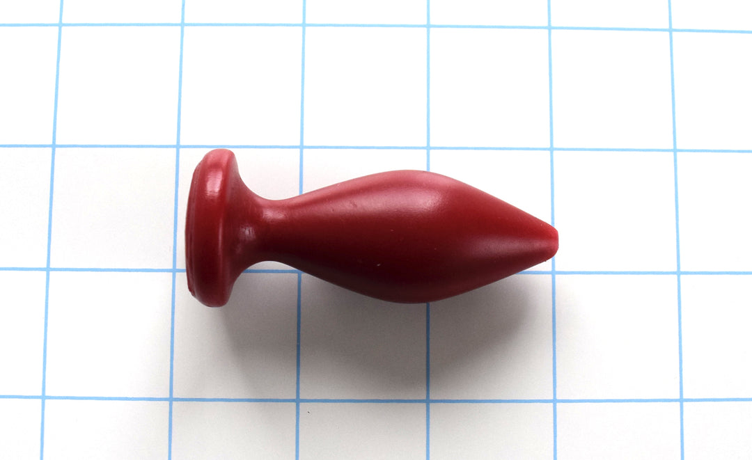 Expanded Diamond 1-inch red silicone retention nozzle featuring a wide faceted diamond body, 2-inch insertable length, ultra-slim retention valley, and flat safety flange on a grid background.