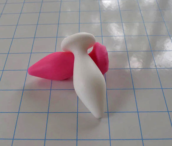 Expanded Diamond 1-inch white silicone retention nozzle with pink accent featuring a wide faceted diamond body, 2-inch insertable length, ultra-slim retention valley, and flat safety flange on a grid background.