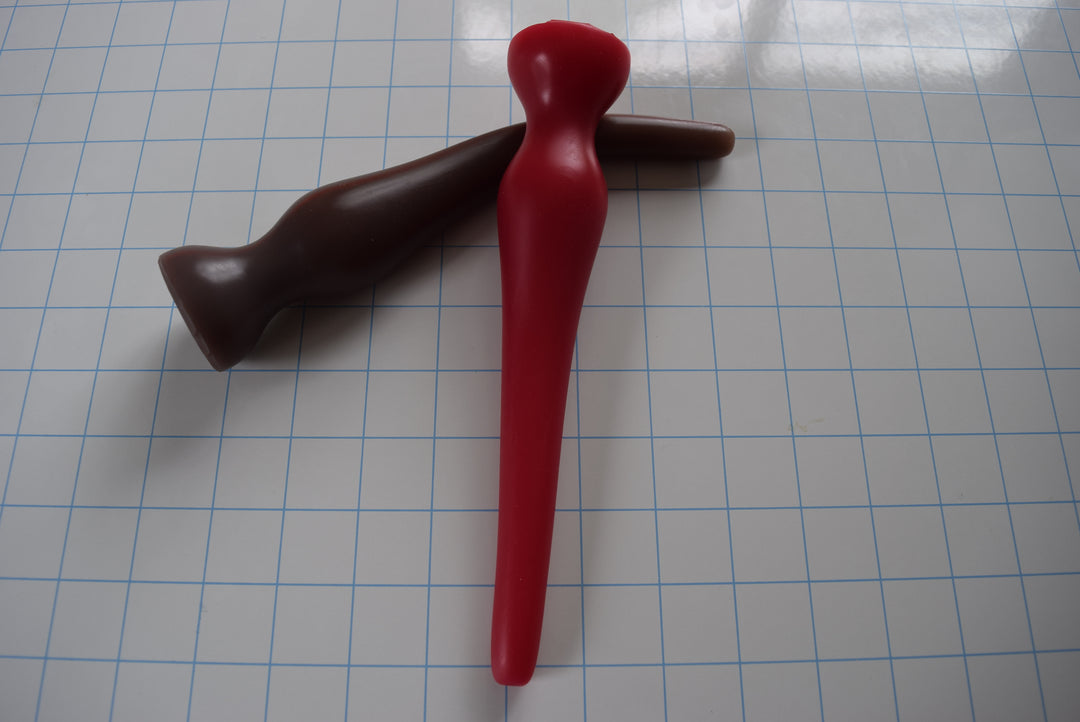 Red and brown EXT CON 1.5 inch silicone retention nozzles crossed over each other on a grid surface.