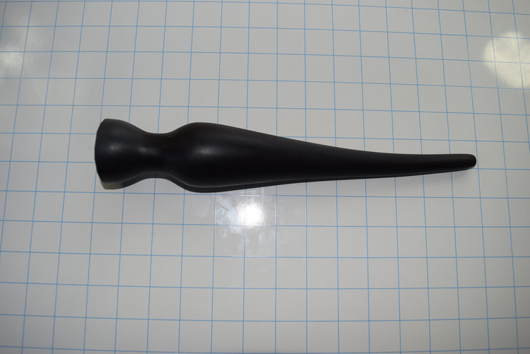 Black EXT CON 2.0 inch silicone enema plug lying horizontally on a blue measurement grid background.
