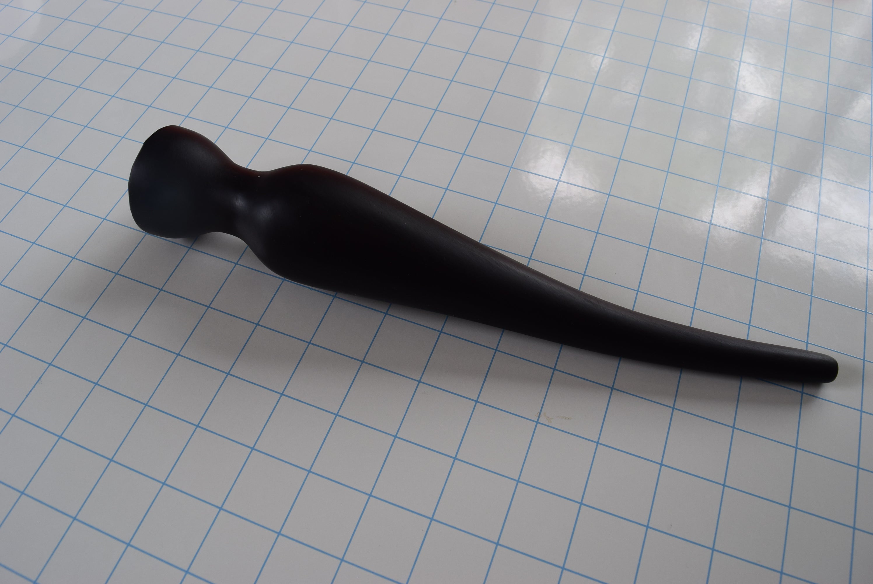 Angled top-down view of a black EXT CON 2.0 inch silicone retention nozzle resting across a grid surface.