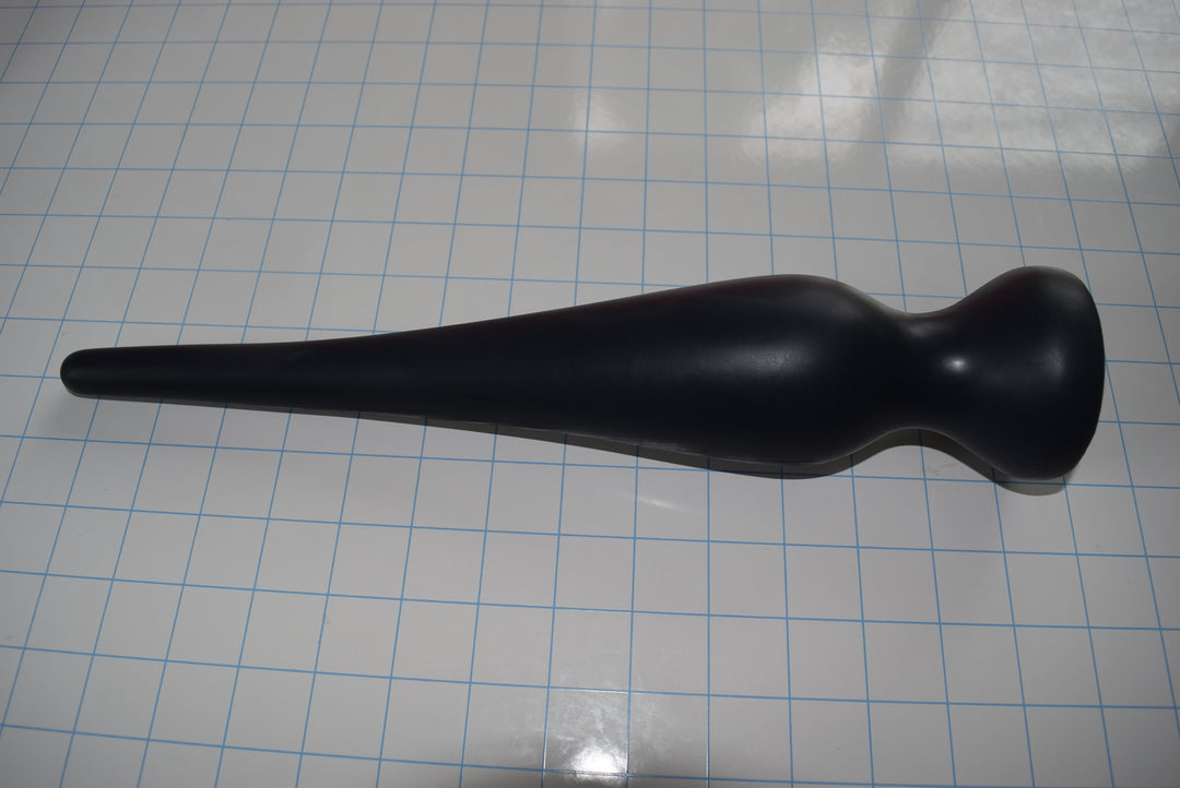Black EXT CON 2.5 inch silicone retention nozzle resting horizontally across a blue measurement grid facing right.