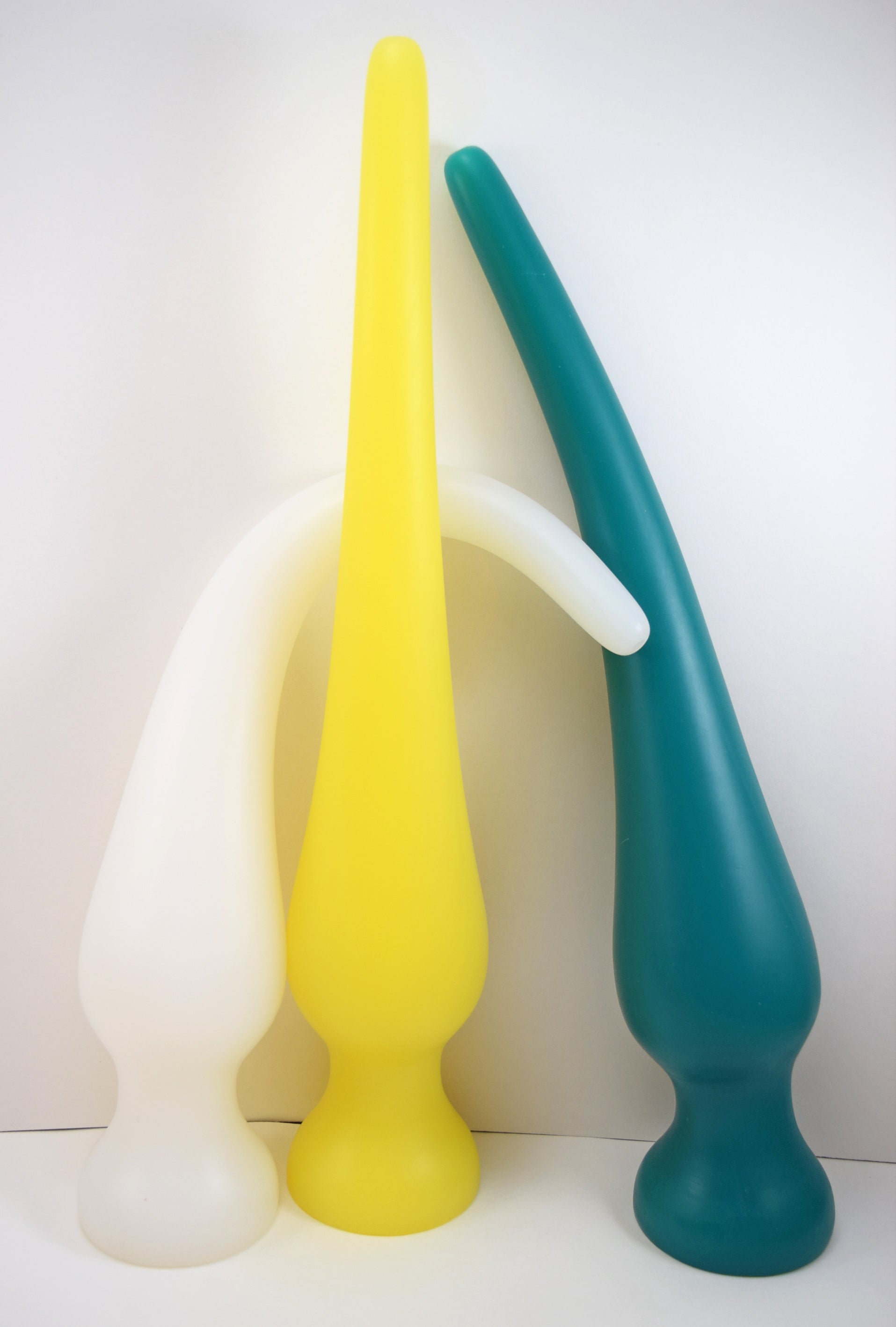Three EXT CON 3.0 inch silicone retention nozzles standing vertically in translucent white, yellow, and teal demonstrating material flexibility.