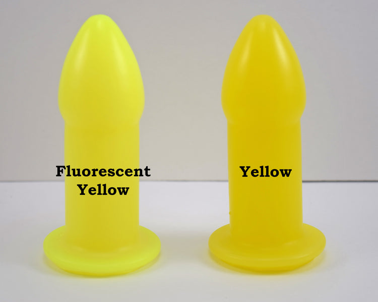 Two silicone nozzle plugs side-by-side on a white surface, demonstrating color differences. The plug on the left is labeled 'Fluorescent Yellow', and the plug on the right is labeled 'Yellow'; both have a tapered tip and wide safety flange