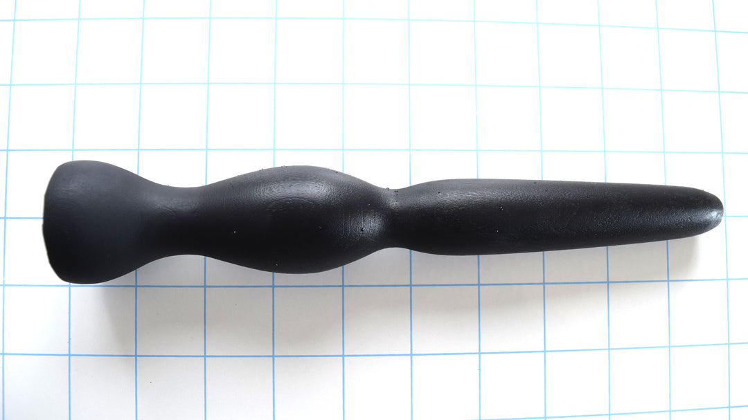 GRB 35 black silicone colon nozzle showcasing its 4.5-inch tapered entry tip, 1.4-inch elliptical expansion ball, dual retention valleys, and 1.5-inch safety flange base on a grid background.