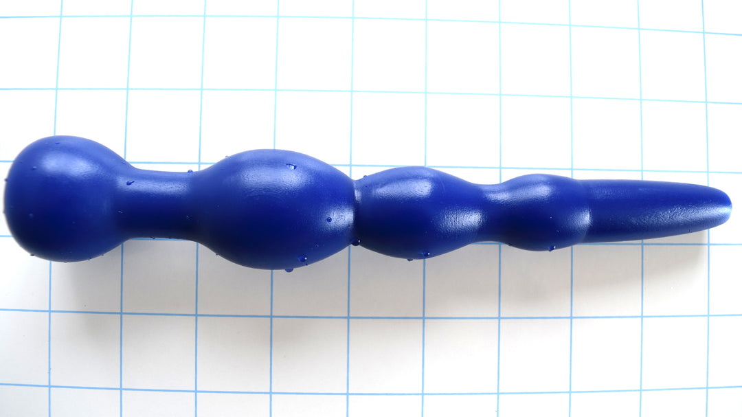 GRB 36 blue silicone enema nozzle on a blue grid background, showcasing its long 2.25-inch tapered tip, three graduated expansion beads, 1.4-inch final oval retention ball, and 7.5-inch insertable length