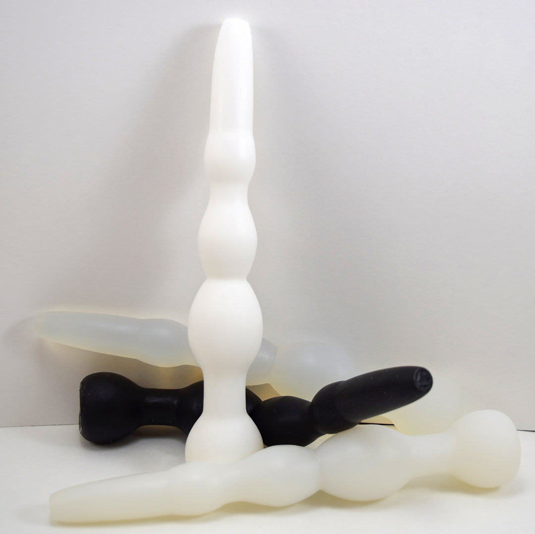 Cluster of GRB 36 silicone colon nozzles in white and black shown standing upright and resting horizontally.