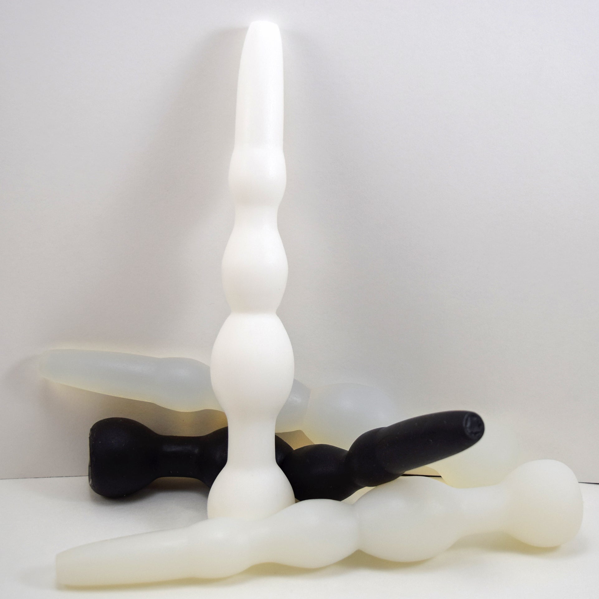 Cluster of GRB 36 silicone colon nozzles in white and black shown standing upright and resting horizontally.