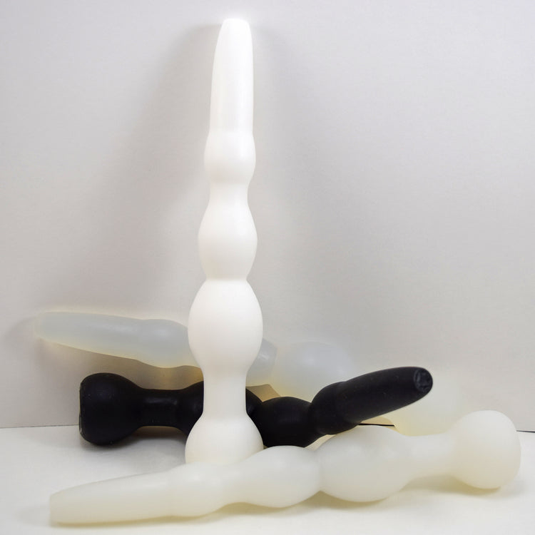 Cluster of GRB 36 silicone colon nozzles in white and black shown standing upright and resting horizontally.