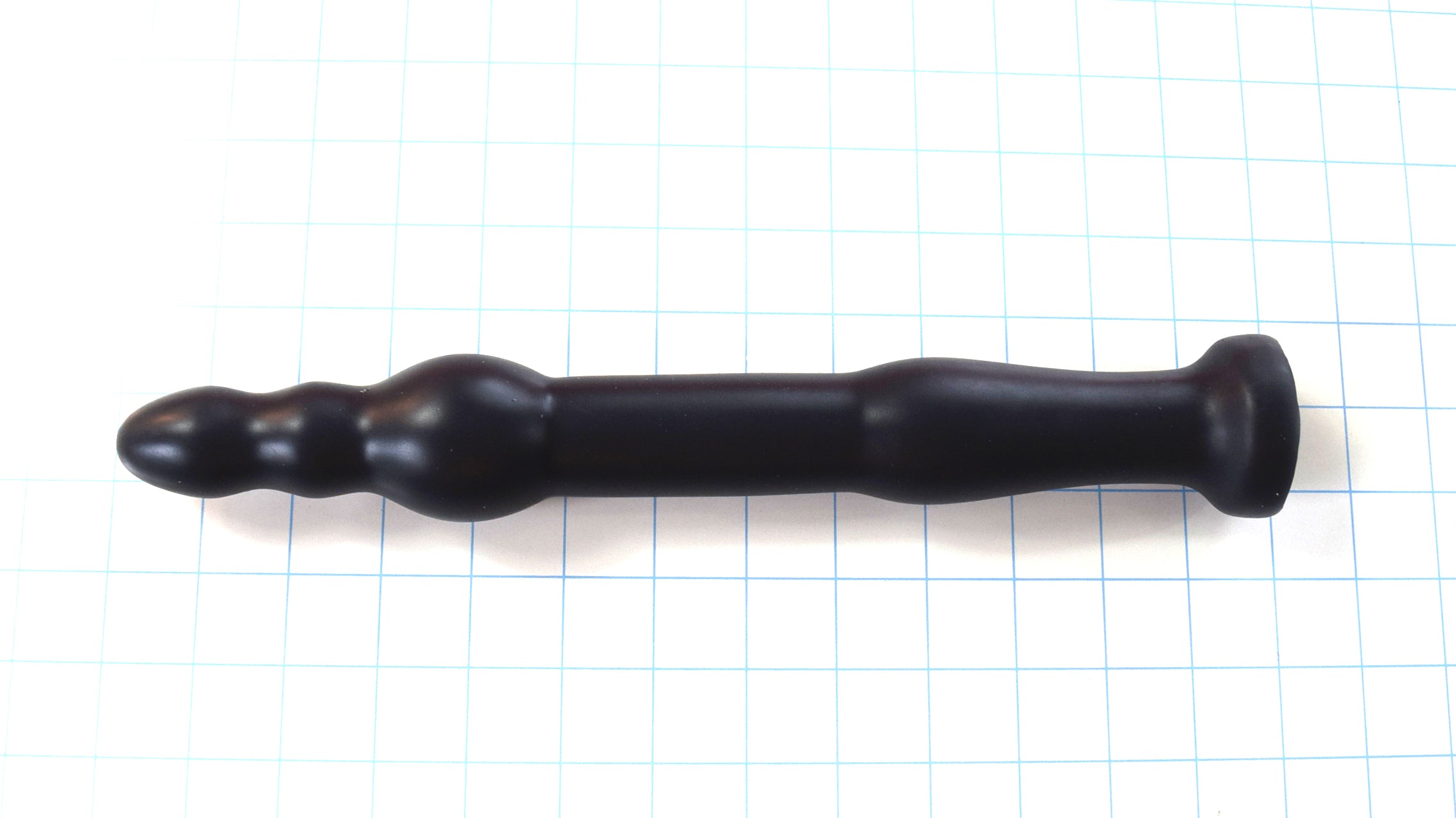 GRB 86 BT 12-inch silicone colon nozzle featuring a segmented ball-tip head with a 1.75-inch anchor ball, 1.3-inch main shaft, dual retention valleys, and a safety base flange on a blue grid background.