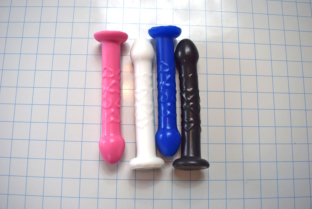 Four colorful dildos on a grid background