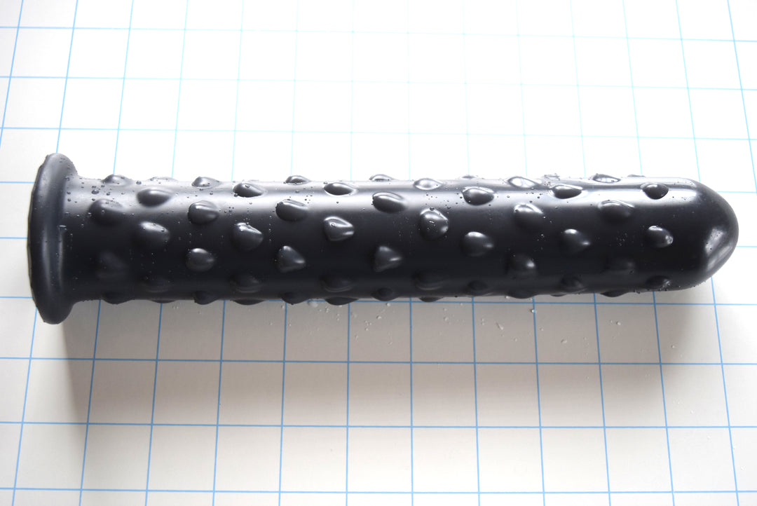 Black silicone Knobby Jumbo nozzle with textured surface, 1.75 inch diameter, and safety flange on a grid background
