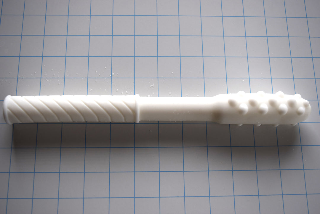 Knobby Tip textured translucent white silicone colon nozzle on a blue grid background, showcasing its 1.75-inch bulbous nodule tip, smooth mid-shaft, and diagonally ribbed base