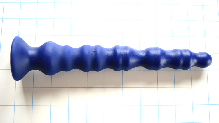 Knuckle 10.5-inch enhanced rib-style colon nozzle in royal blue silicone on a blue grid background, highlighting its five dual-groove knuckle segments and wide flared safety base