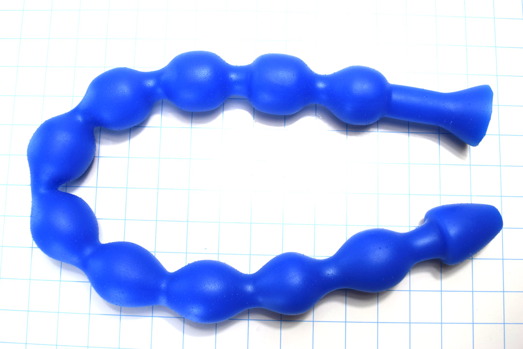 MAXIBALL 30-inch blue silicone colon tube showing ten segmented 1.8-inch retention bulbs, a tapered tip, and a 1.9-inch safety flange coiled on a blue grid background