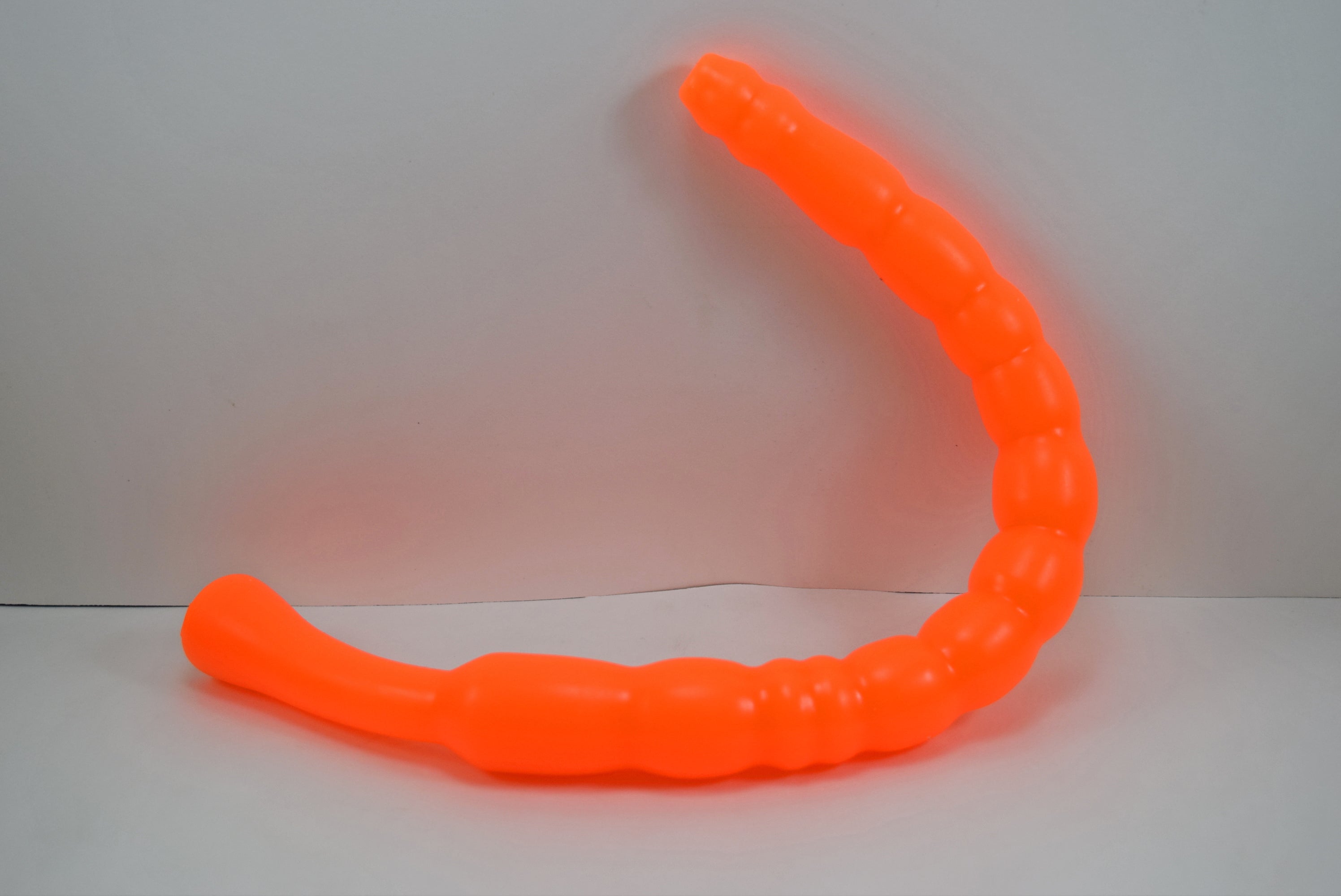 Bright orange MBXL ribbed silicone colon nozzle, showcasing its flexible, graduated design and flared base flange on a clean white background
