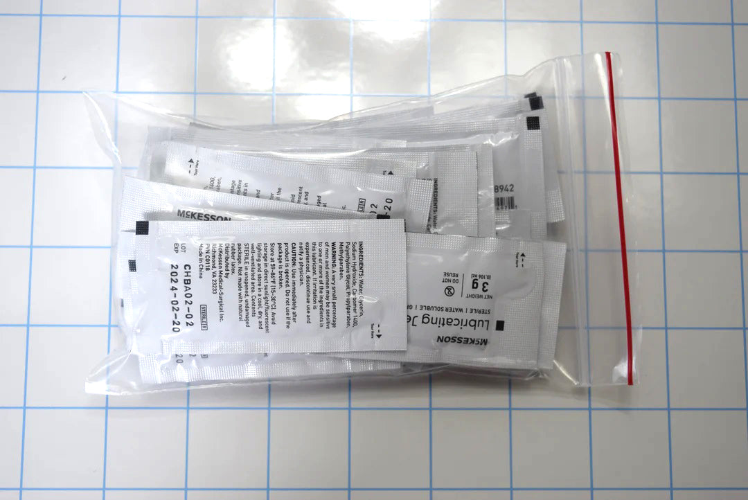 25-count pack of McKesson 3g sterile lubricating jelly foil packets in a clear bag on a grid background