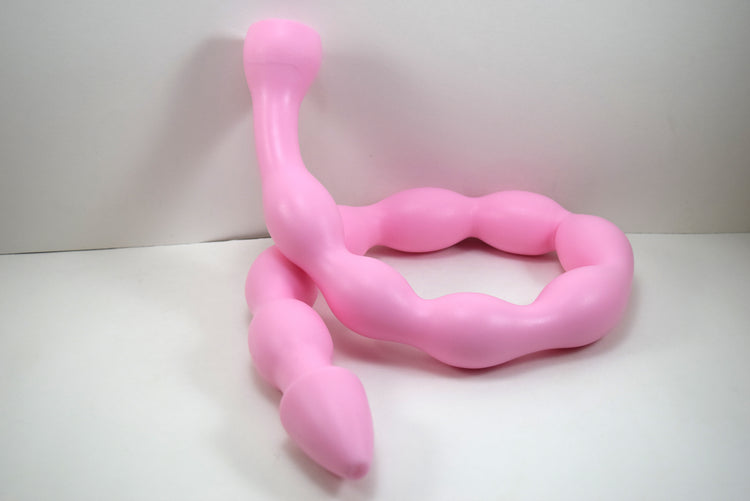 MINIBALL 31-inch pink silicone colon tube showing ten segmented 1.6-inch retention balls, a tapered tip, and a 2-inch safety flange coiled on a white surface