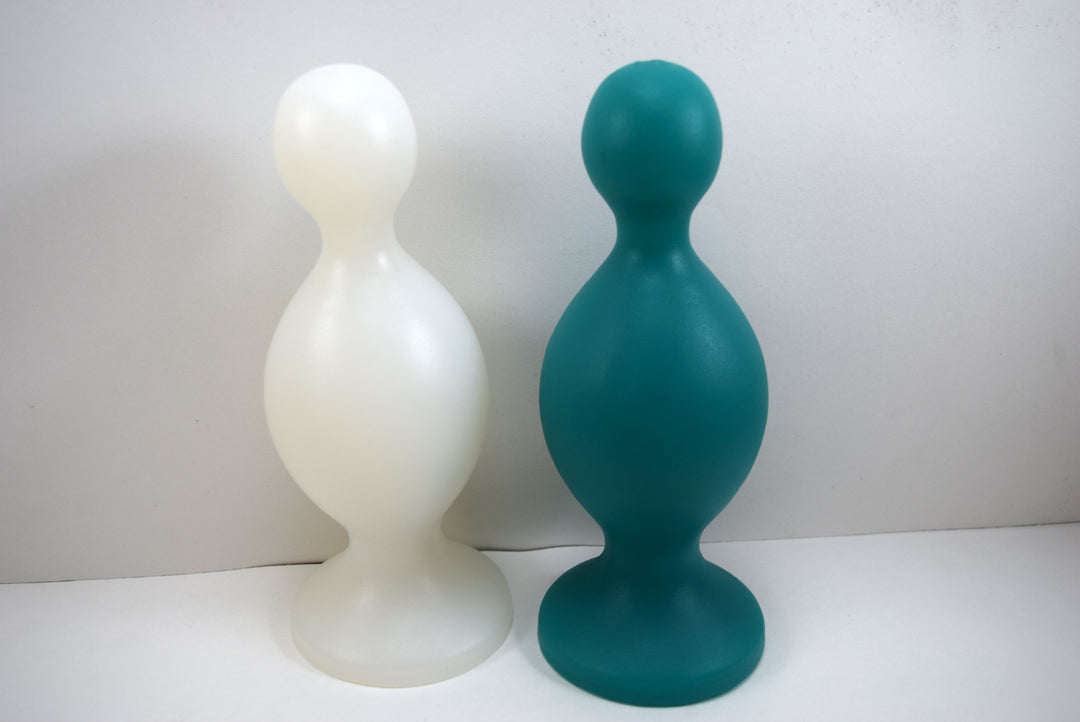 Two MiniMax silicone retention nozzles shown standing upright in natural translucent-white and teal green, showcasing the 1.5-inch tip, 2.8-inch main bulb, and wide safety flange