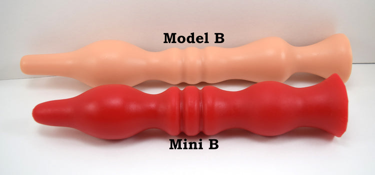 Flesh-colored Model B enema nozzle lying parallel to a red Mini B silicone nozzle on a white background.