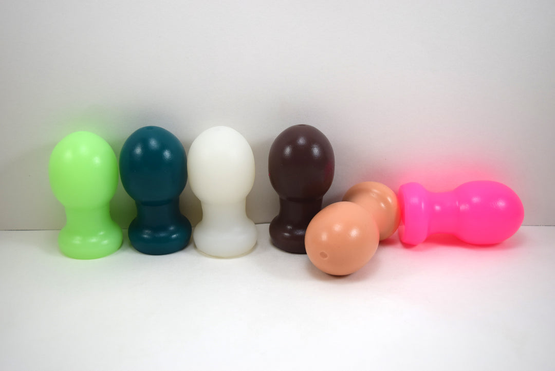 A collection of six Model EX silicone nozzles displayed in a row on a white background, showing vibrant color options including lime green, teal, translucent white, brown, flesh tone, and hot pink to highlight the 1.8-inch ball tip design