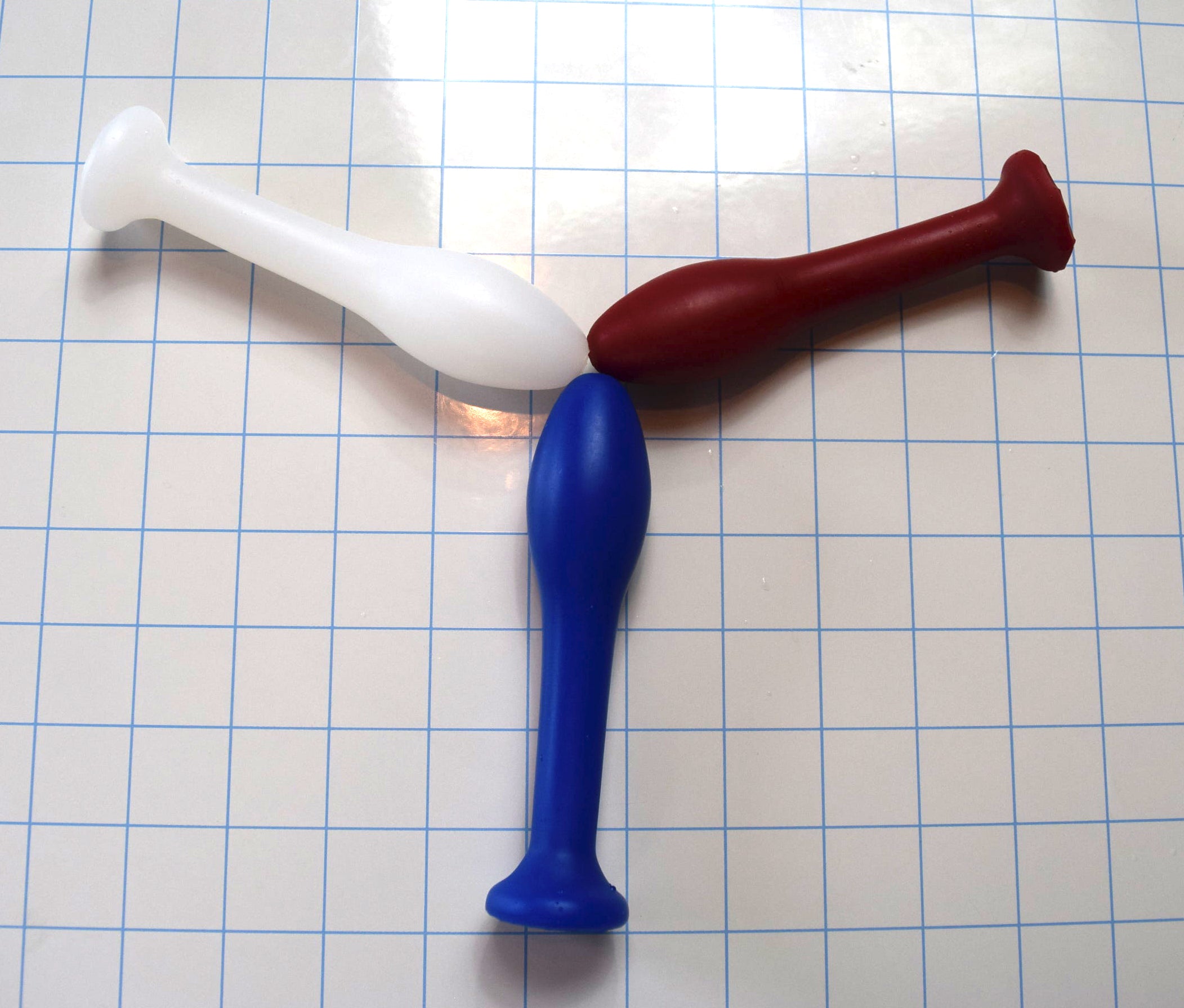 Three 1.2-inch Classic Model M silicone enema nozzles in white, red, and blue arranged tip-to-tip on a grid background.