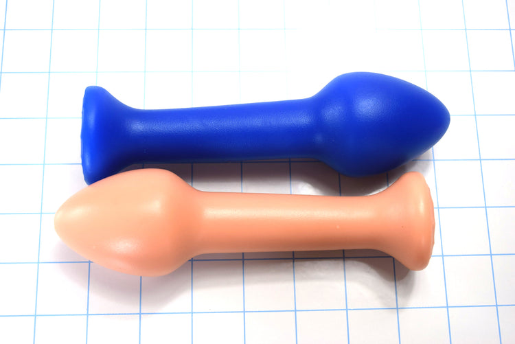 Two Model Y 2-inch silicone retention nozzles shown in blue and peach, highlighting the large 2-inch bulbous tip and elongated retention shaft on a grid background