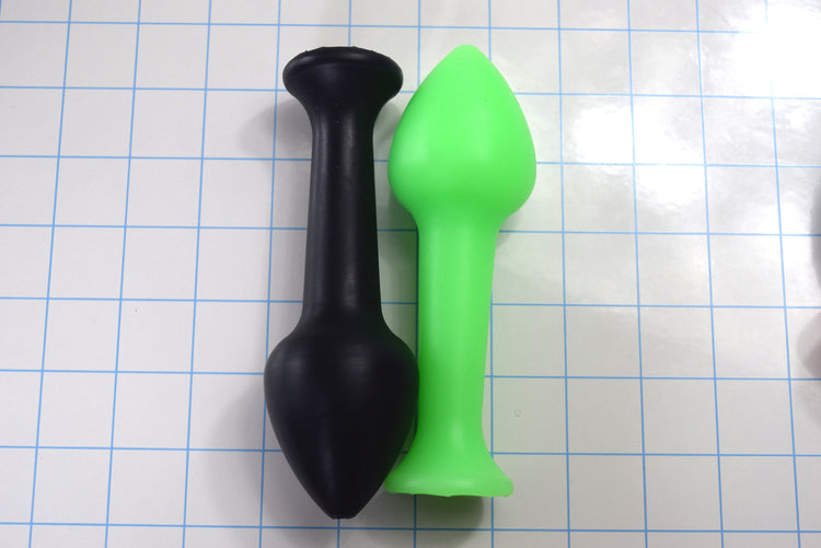 Black and green Model Y features a large 2" tapered tip for excellent stability and sensation. Fully customizable firmness, color, and bore size for a perfect fit, on a grid background