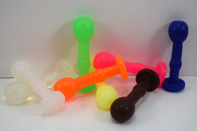 Assorted colorful Nubby Ext compact silicone enema nozzles in neon green, orange, pink, blue, brown, yellow, and translucent white.
