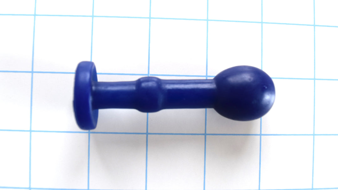Nubby Ext extended blue silicone retention plug showing the dual-bulb design, straight mid-shaft, and flat safety flange on a blue grid background