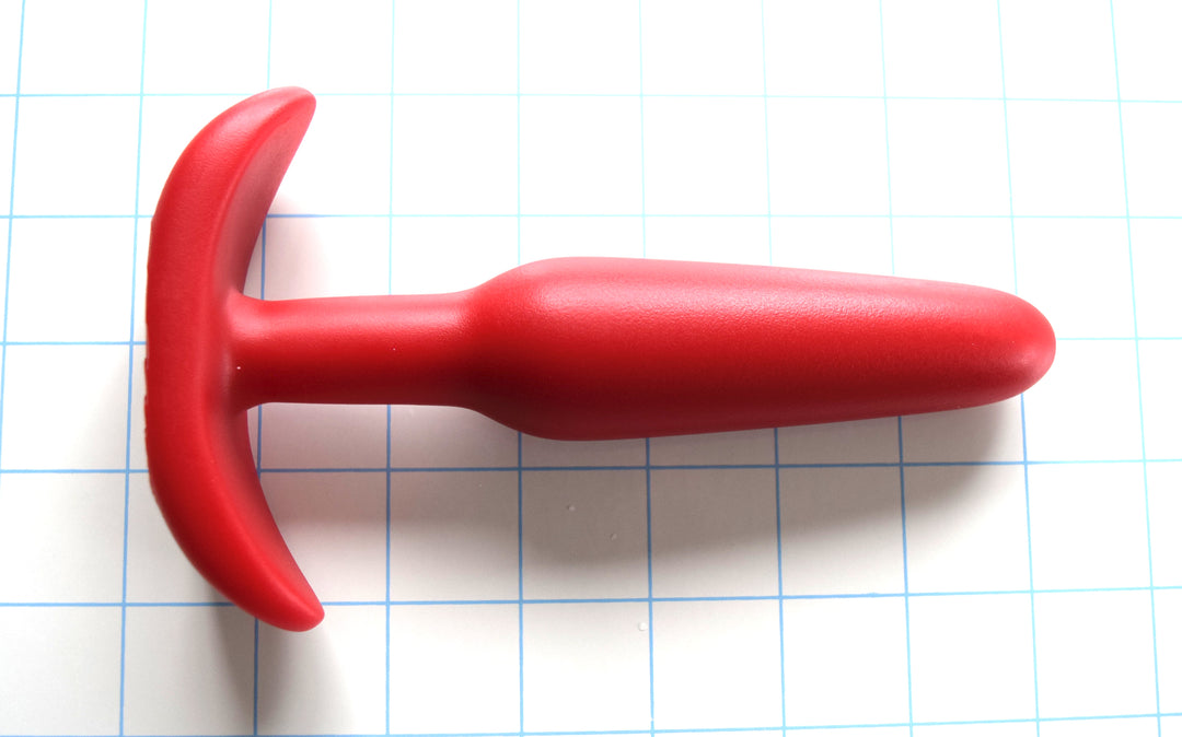 OF 1.3 red silicone retention enema nozzle showing its 1.3-inch maximum diameter shaft swell, 0.75-inch retention valley, and 4-inch wide ergonomic oval flange on a grid background