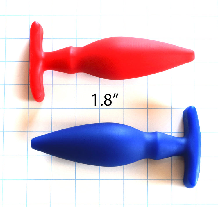 1.8-inch OF Wing silicone enema nozzle on a grid background showing the red and blue variants, curved body, retention valley, and winged base flange