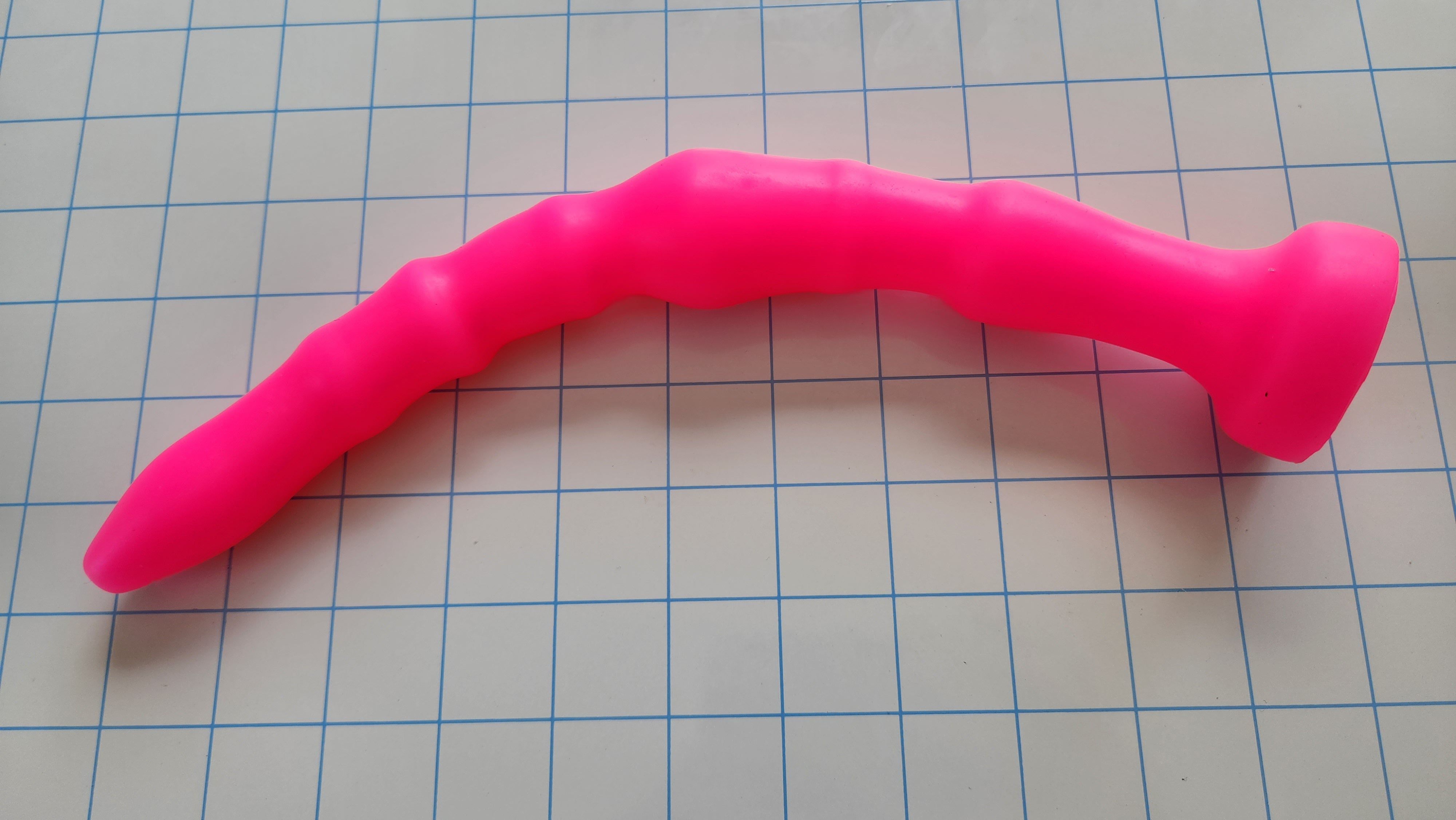 Reverse curve view of the pink Off-Centered 11-inch silicone colon tube showcasing its six undulating eccentric ribs and safety flange.