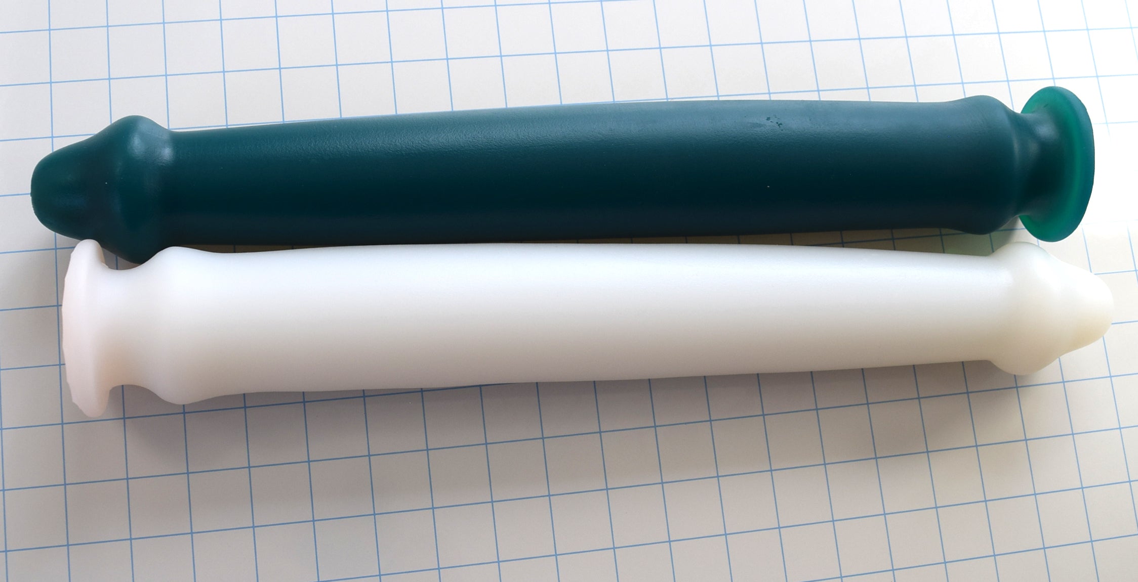 Priapus 18-inch large silicone enema nozzle lineup featuring dark green and white models with 17-inch insertable lengths, 2.5-inch maximum shaft diameters, and safety retention flanges on a blue grid background.
