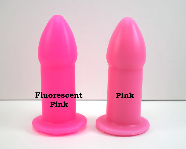 Fluorescent pink and standard pink silicone rectal training dilators standing side-by-side on a white surface with text.